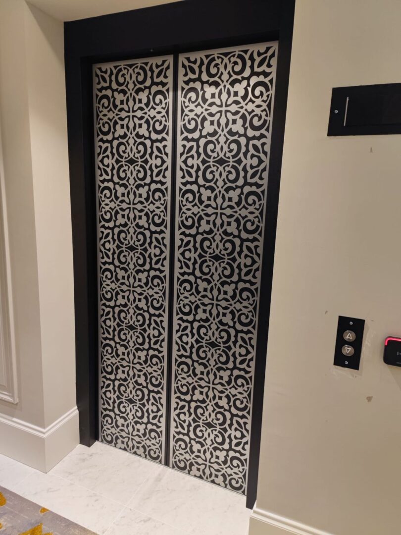 A black and white elevator door with ornate designs.