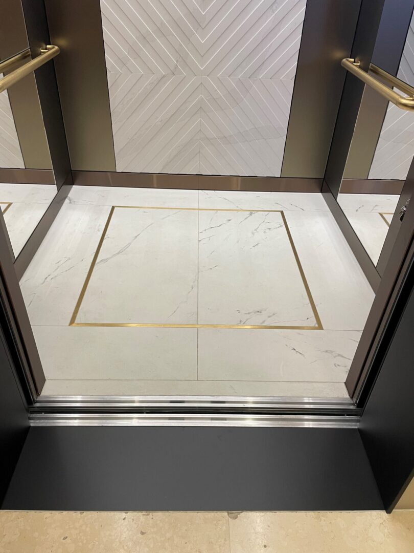 A lift with marble floors and gold trim.