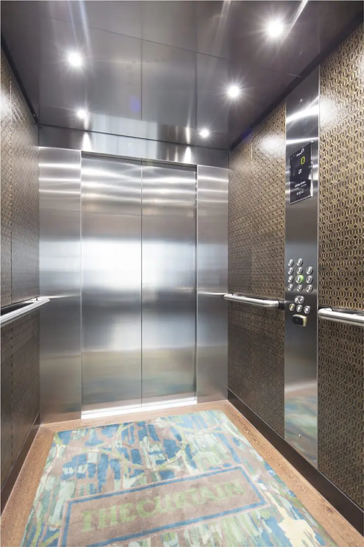 A large metal elevator with two doors and a rug.