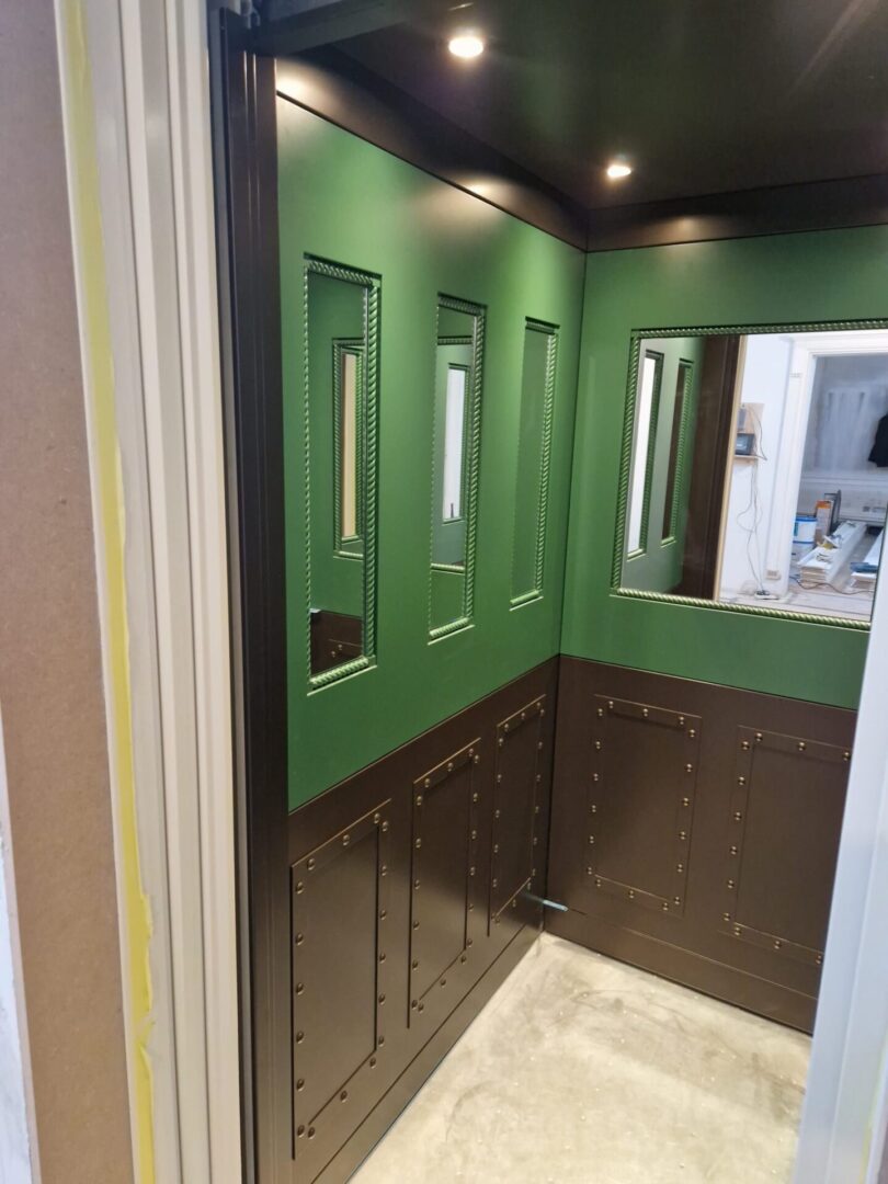 A green and brown bathroom with mirror, cabinets and tiled floors.