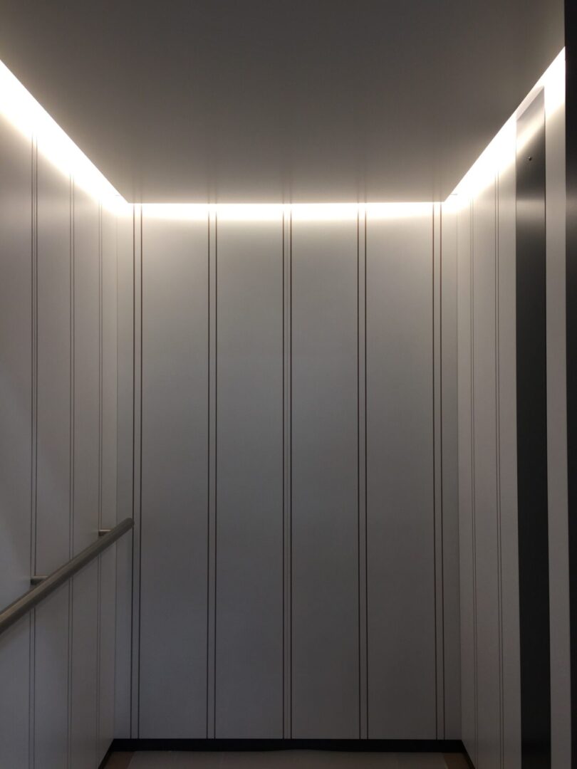 A white elevator with lights on the side of it.